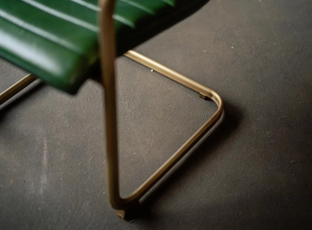 Detailansicht: Leder Freischwinger mit einem Messing Gestell.