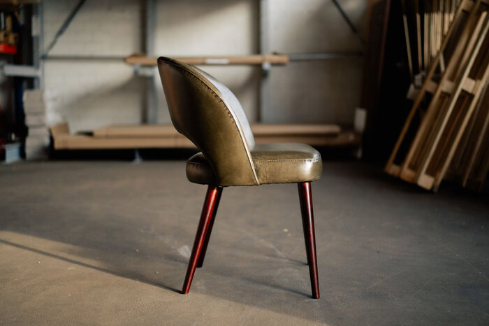 Retro Stuhl aus Echtleder mit Holzbeinen gefertigt.