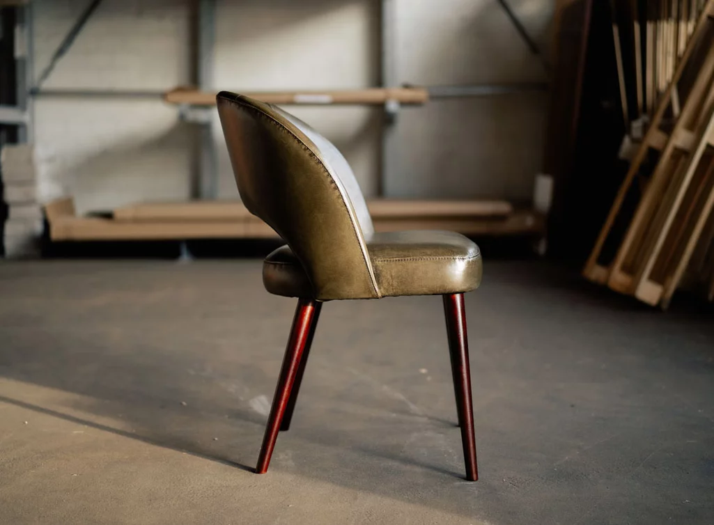 Retro Stuhl aus Echtleder mit Holzbeinen gefertigt.