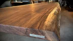 Holzpiloten-Schild auf der Stirnseite der Kambala Tischplatte mit natürlicher Baumkante | © © 2025 Holzpiloten